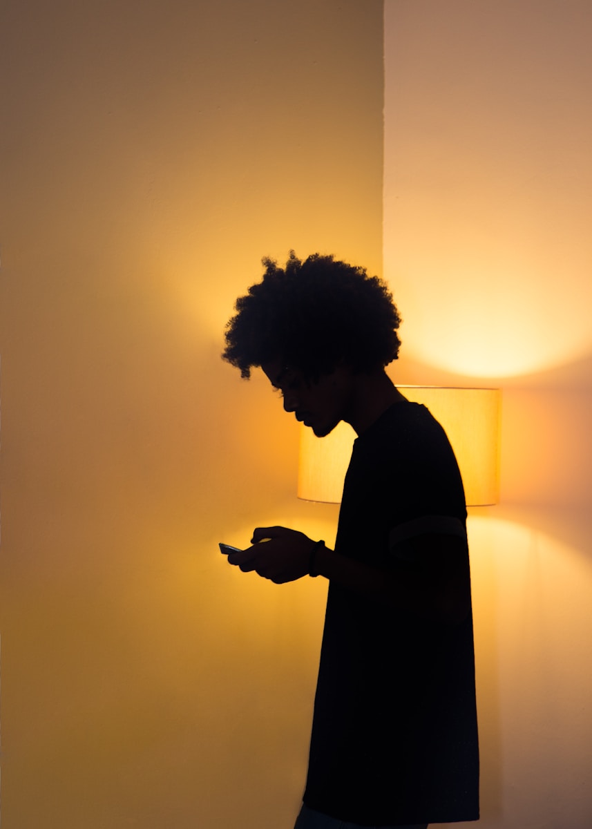 a man standing in front of a lamp using a cell phone